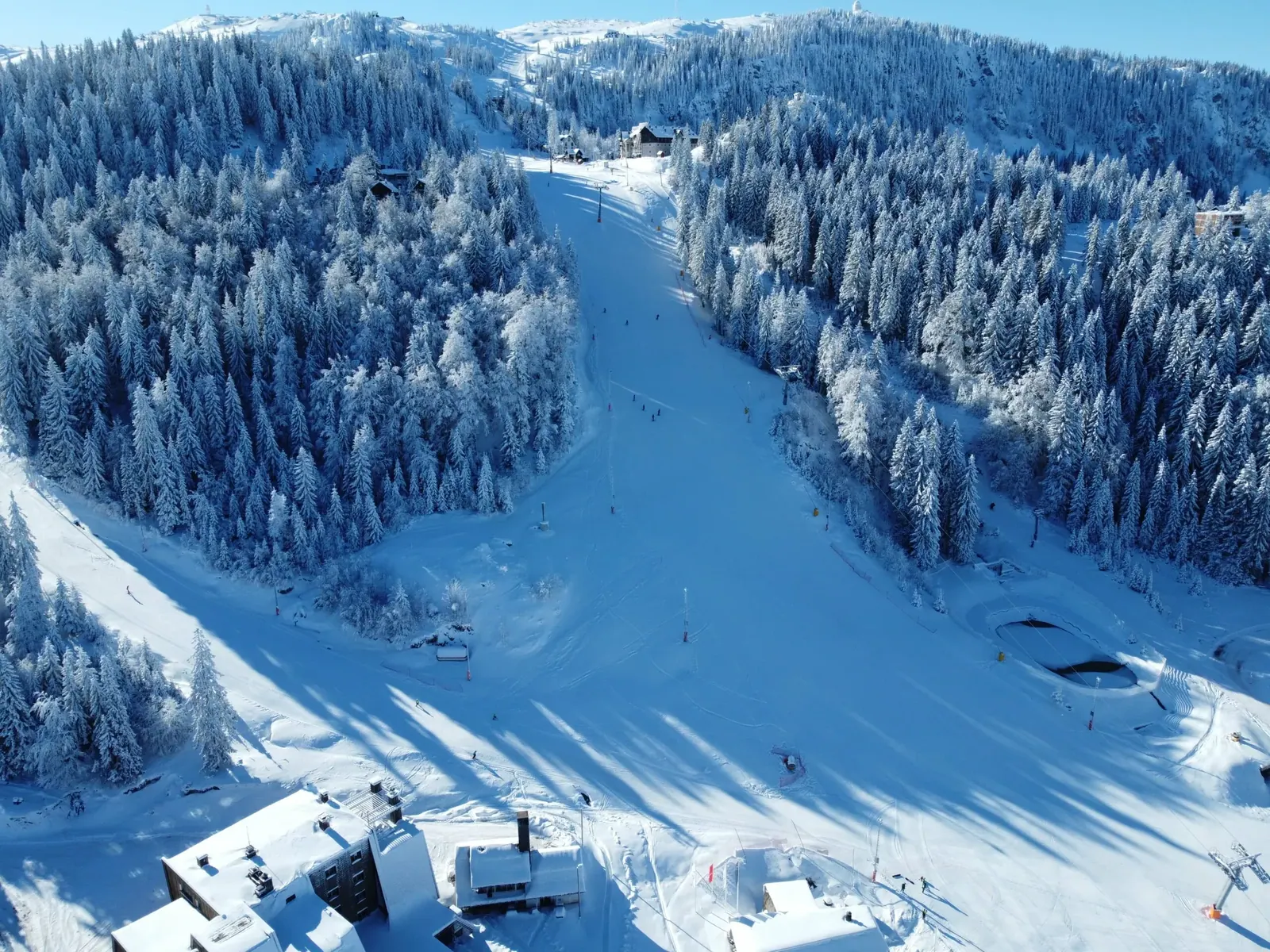 Skijaška staza na planini Jahorini okružena snijegom prekrivenom šumom