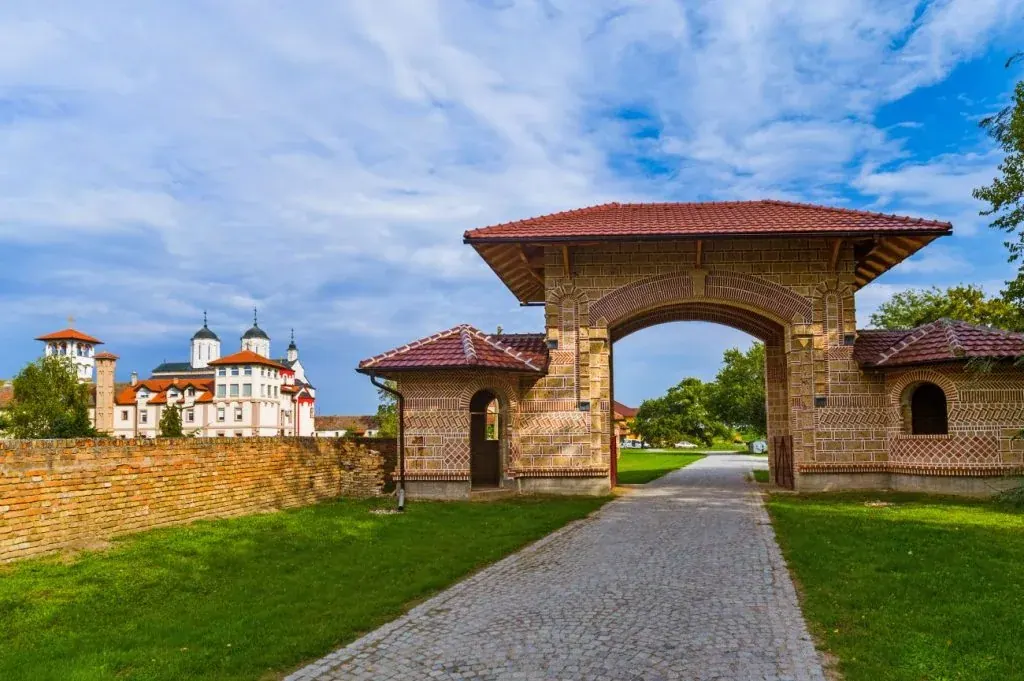 Manastir na Fruškoj gori Historijski manastirski kompleks i ulazna kapija okruženi zelenim brdima Fruške gore